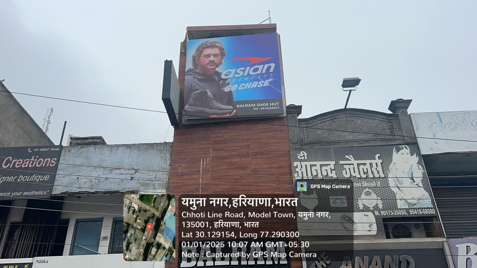 A rectangular billboard mounted on a brick wall, featuring a colorful advertisement non-lit board