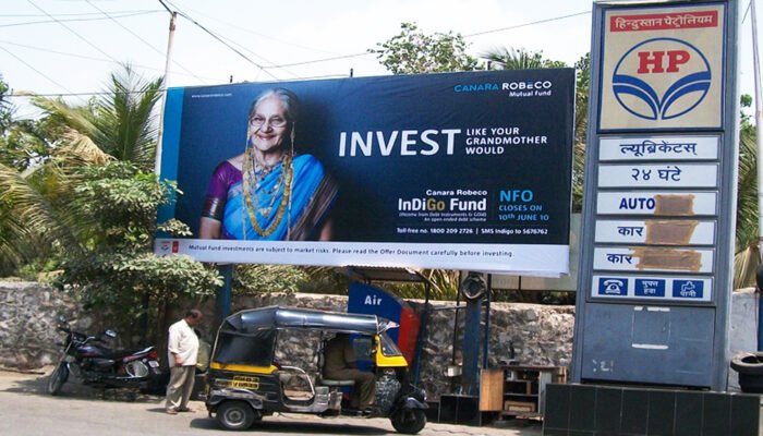 Petrol Pump Advertising: Canara Robeco Mutual Fund Billboard Featuring Indigo Fund Campaign Petrol pump advertising for Canara Robeco Indigo Fund featuring elderly woman visual and NFO promo targeting fuel station visitors.